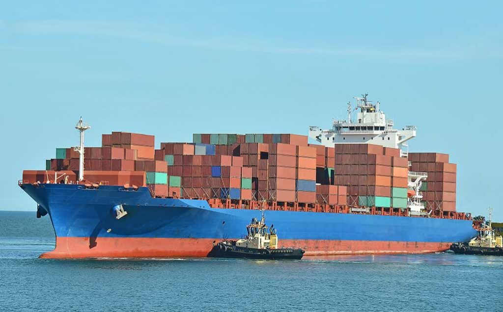 cargo ship being moved by tugboats